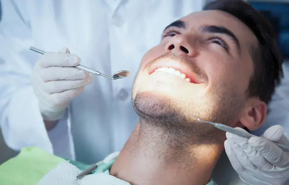 Dentist examining patient's teeth during routine dental checkup and oral care visit.