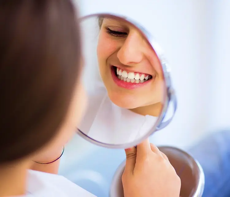 woman reviewing her teeth on mirror after treatment