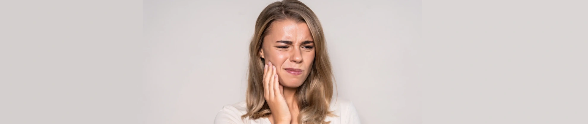 Woman holding her cheek due to tooth pain