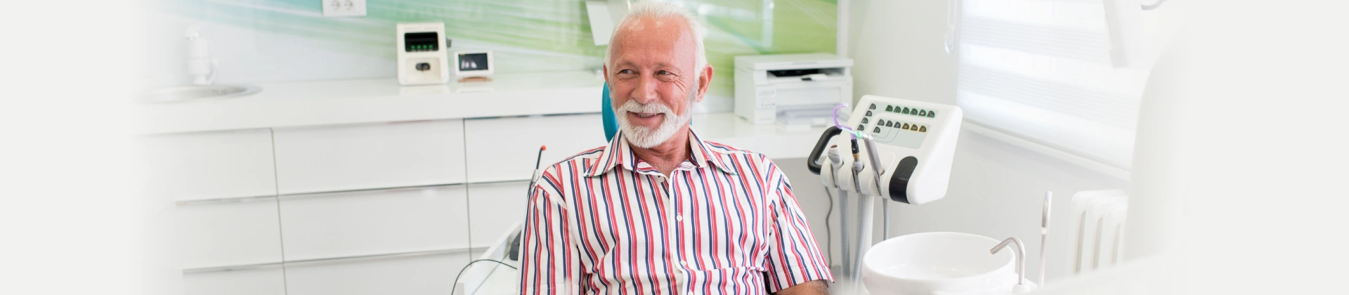 Smiling older man seated in a dental chair.