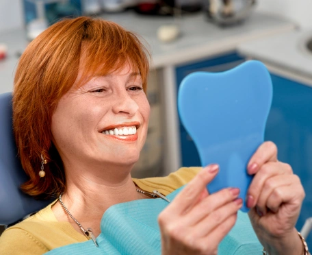 Happy patient smiling while looking in a mirror