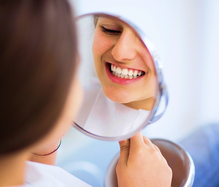 woman reviewing her teeth on mirror after treatment