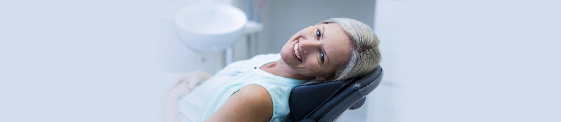 Smiling woman reclining comfortably in a dental chair